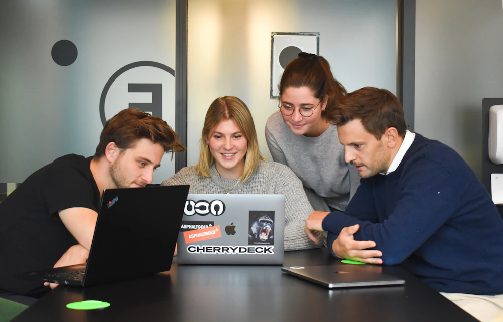 Team collaborating around a laptop in a modern office