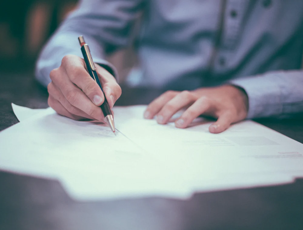 Hands signing a document at a desk