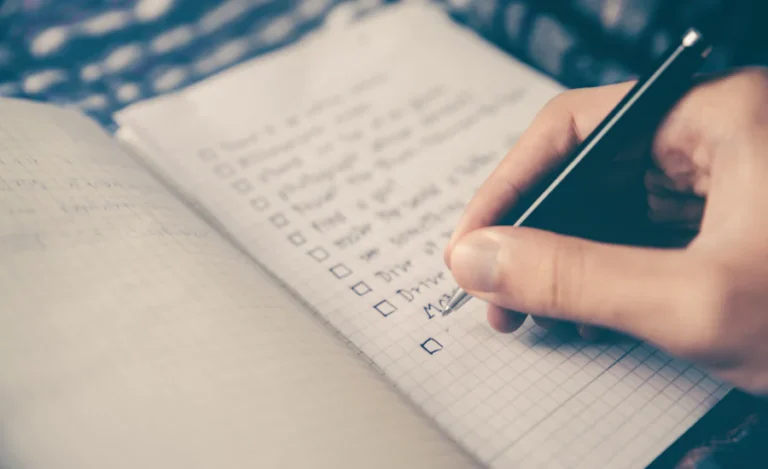 A hand working through a checklist in a notebook